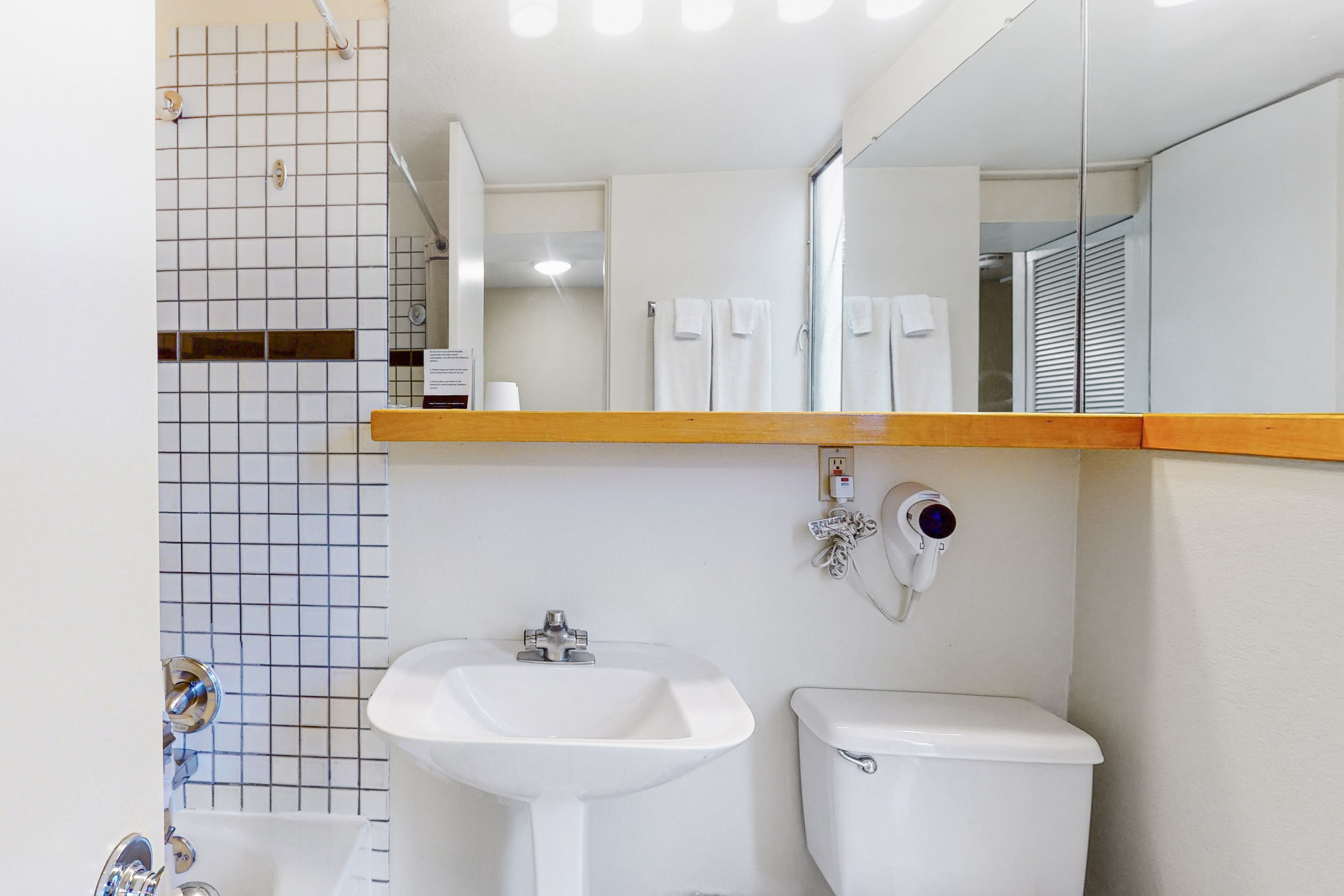 A bathroom with a white sink, toilet, and a mirror above the sink.