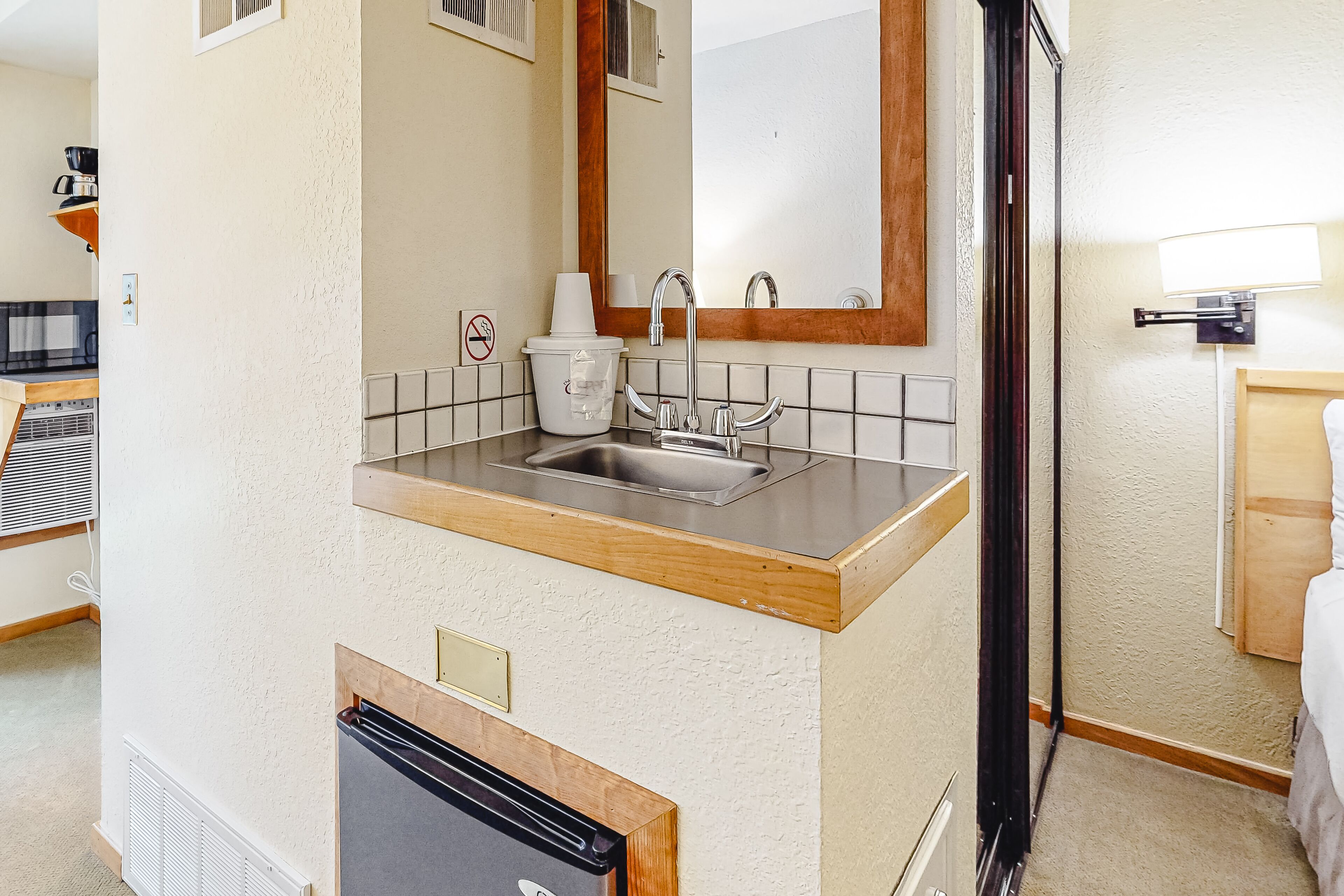 A compact kitchenette with a sink, a microwave, and a small refrigerator.