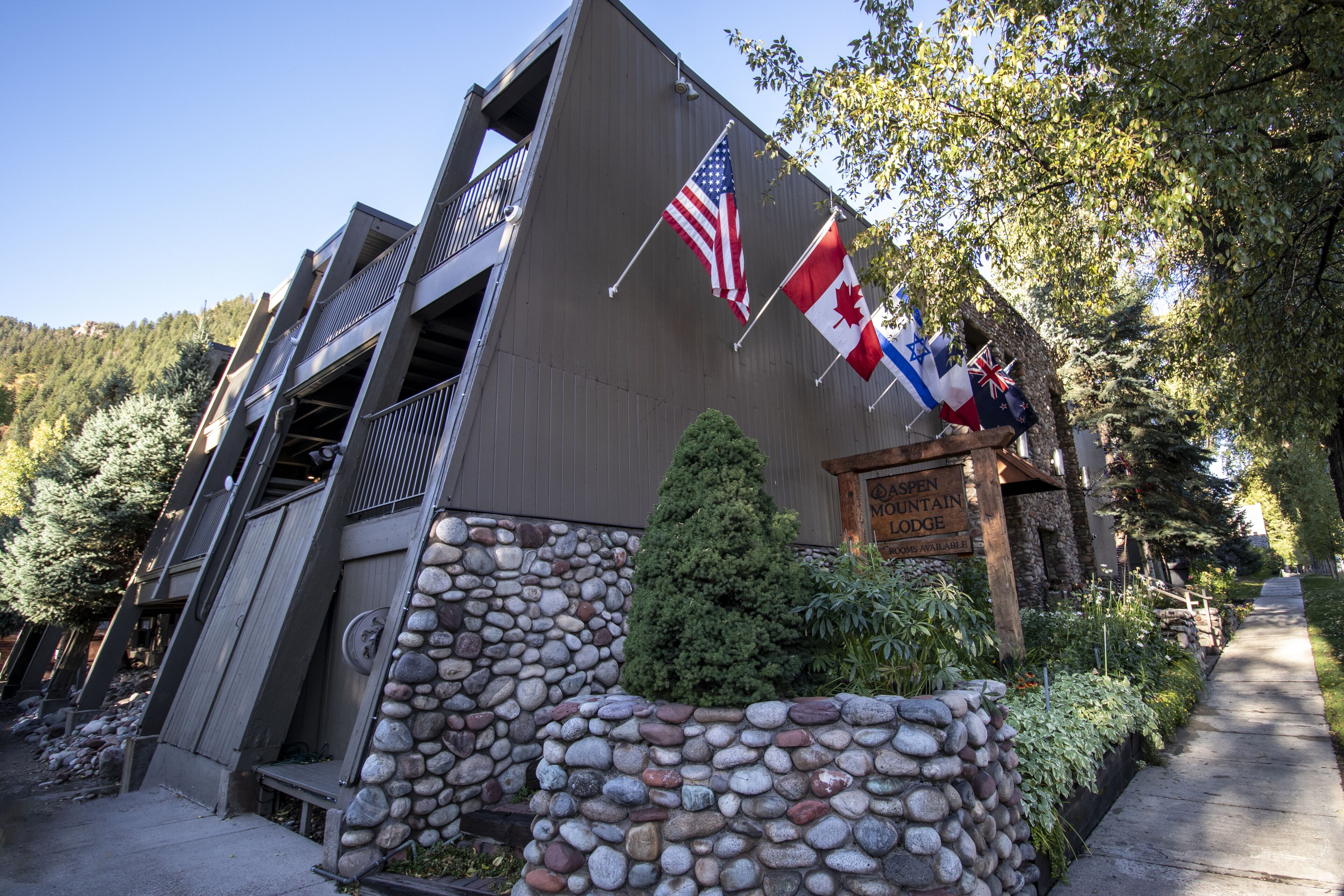 A building with a stone wall, flags, and a sign for 'Spen Mountain Lodge'.
