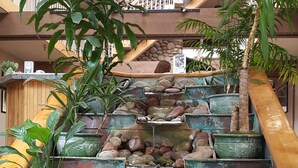 A multi-level indoor waterfall feature with various plants and rocks. - Aspen Mountain Lodge (Aspen)