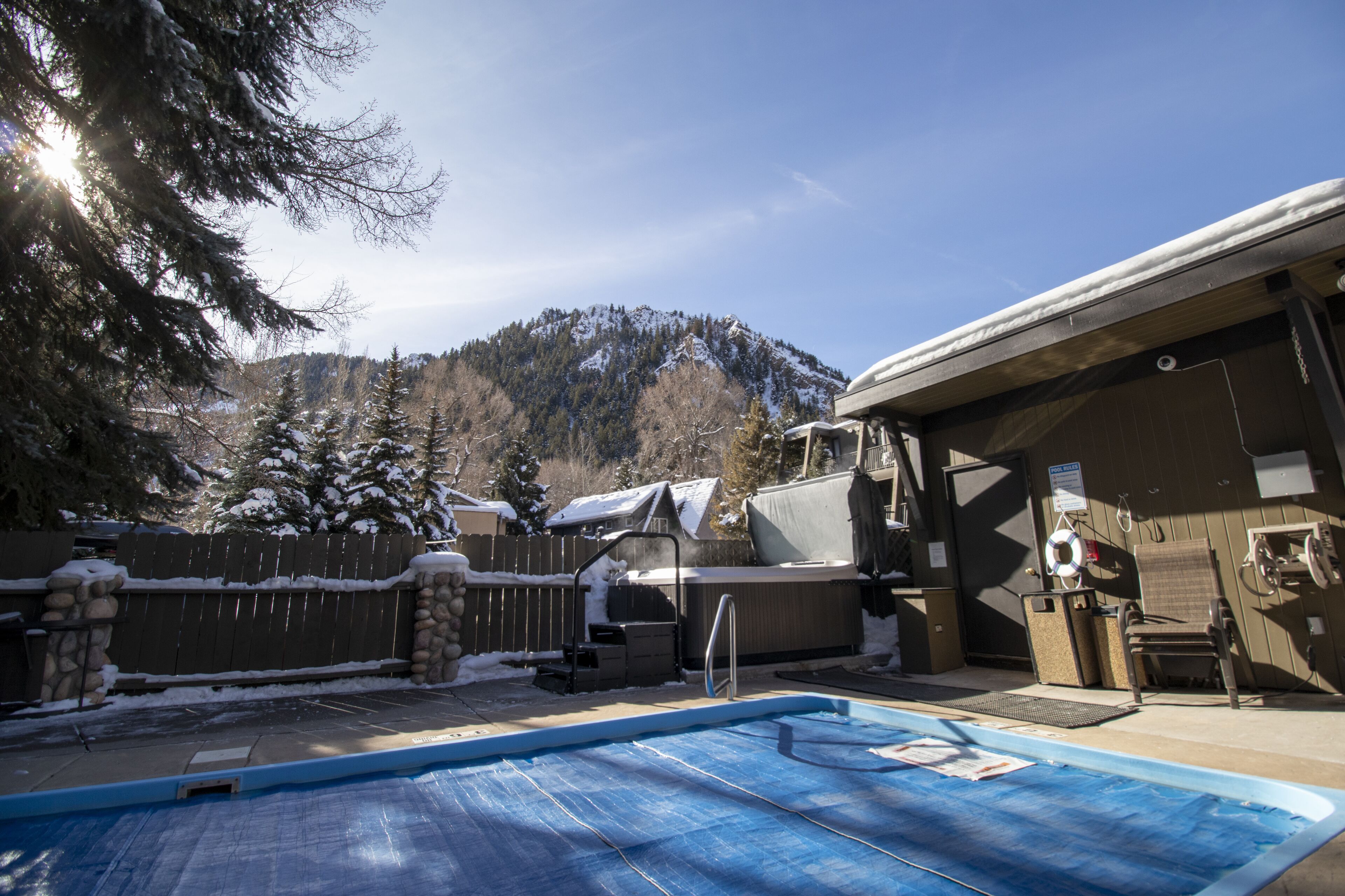 Ein Garten mit Schwimmbecken, Whirlpool und überdachter Terrasse.