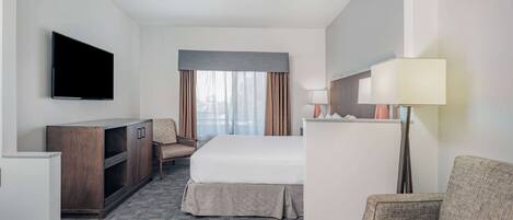 A hotel room with a bed, a desk, a television, a lamp, and a chair.