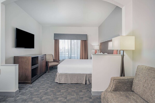 Una habitación de hotel con una cama, un escritorio, un televisor, una lámpara y una silla.