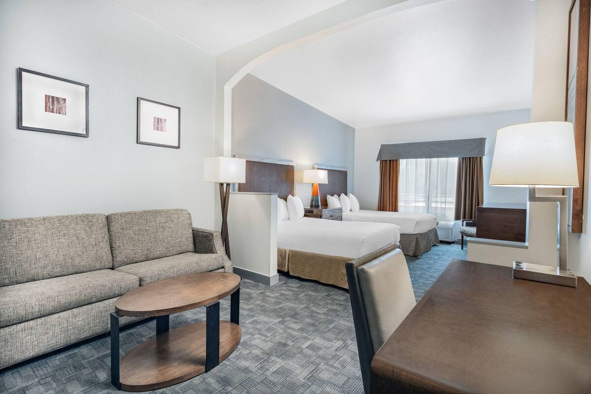 Ein Hotelzimmer mit einer Couch, einem Bett, einem kleinen Tisch und zwei Lampen.