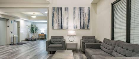 A modern living room with a grey sectional sofa, two armchairs, a coffee table, and abstract wall art.