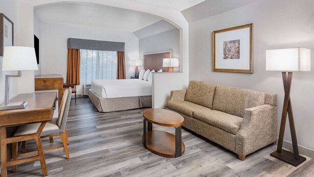 Une chambre d’hôtel comprenant un lit, un canapé, une table à manger et une petite table ronde.