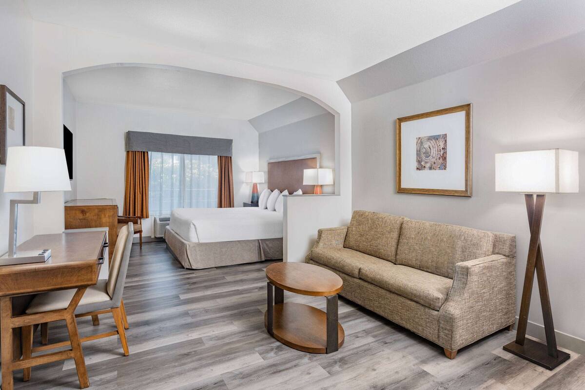 Ein Hotelzimmer mit Bett, Sofa, Esstisch und einem kleinen Rundtisch.