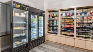 Un distributeur automatique de collations et de boissons, un présentoir réfrigéré et des étagères remplies de divers produits emballés.