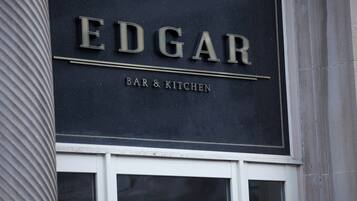 A sign for 'EDGAR BAR & KITCHEN' with a classic design and a window below.