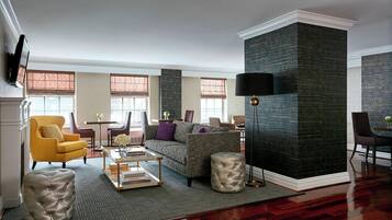Un amplio salón con sofá, sillones, una mesa de centro y una pared grande de color oscuro.