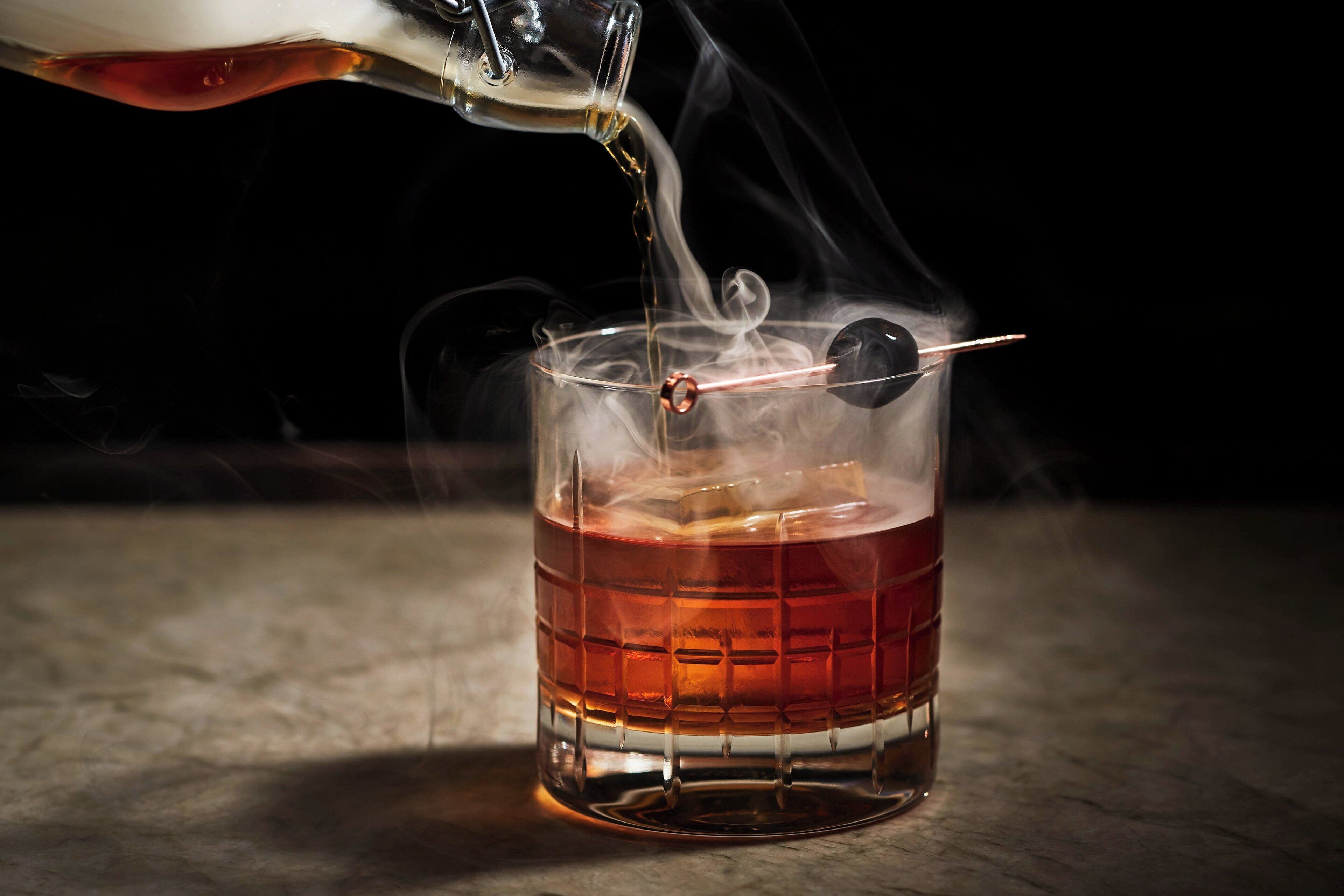 A glass with a cube pattern, filled with a liquid, and a straw inserted.