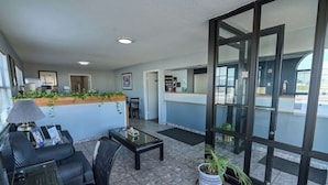 A reception area with a counter, chairs, a coffee table, and potted plants. - Americas Best Value Inn Meridian (Meridian)