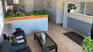A hotel lobby with a reception desk, seating area, and a kitchen in the background. - Americas Best Value Inn Meridian (Meridian)