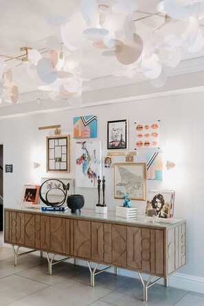 A modern interior with a glass-top console table, wall art, and a unique ceiling light fixture. -  Le Parc at Melrose (West Hollywood)