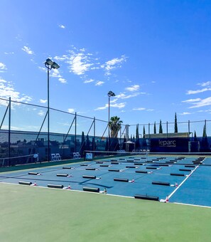 A tennis court with a net, seating area, and a fence. -  Le Parc at Melrose (West Hollywood)