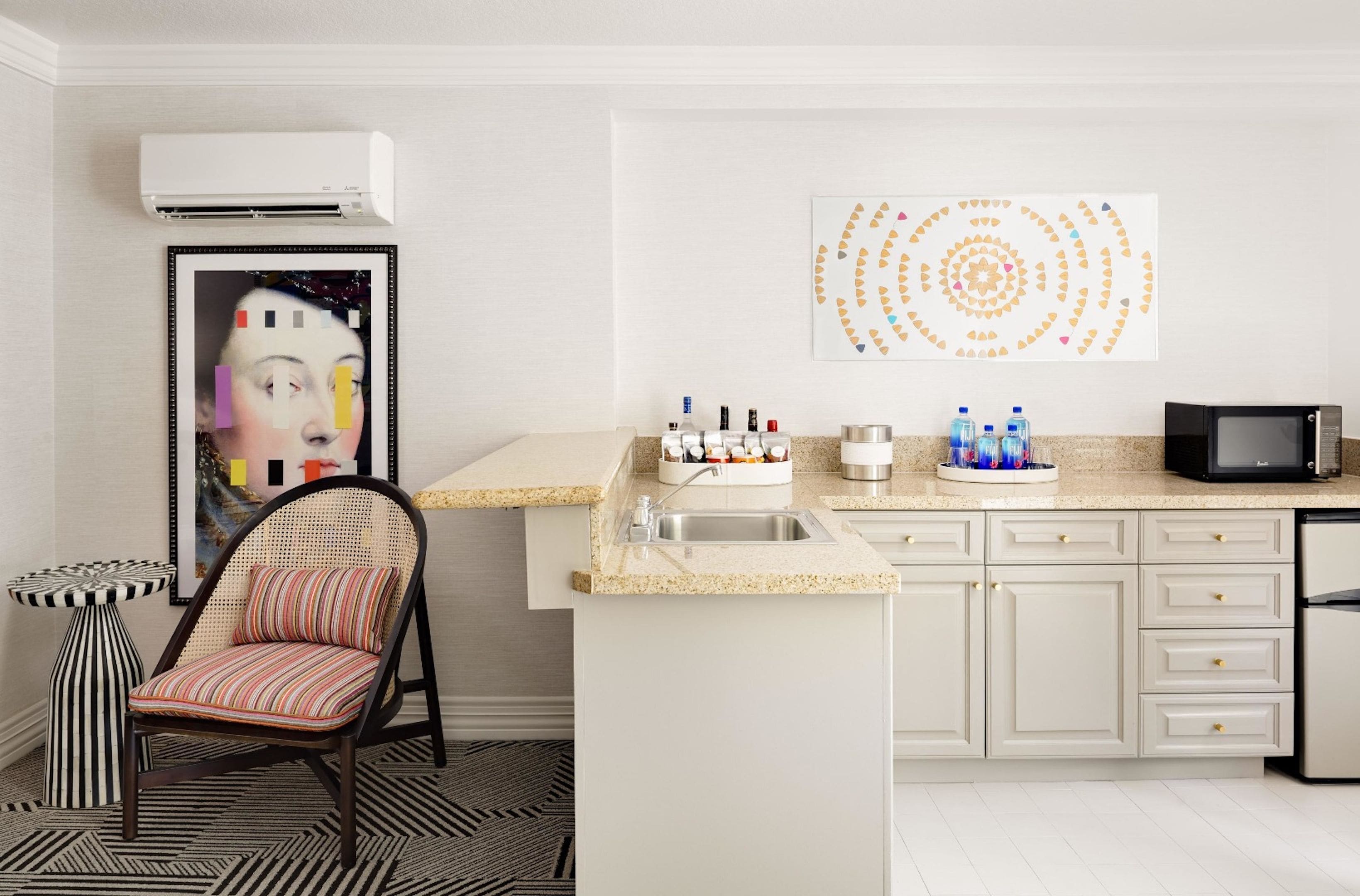 Une cuisine moderne équipée d’un four à micro-ondes encastré, d’un évier et d’un élément d écoratif mural.