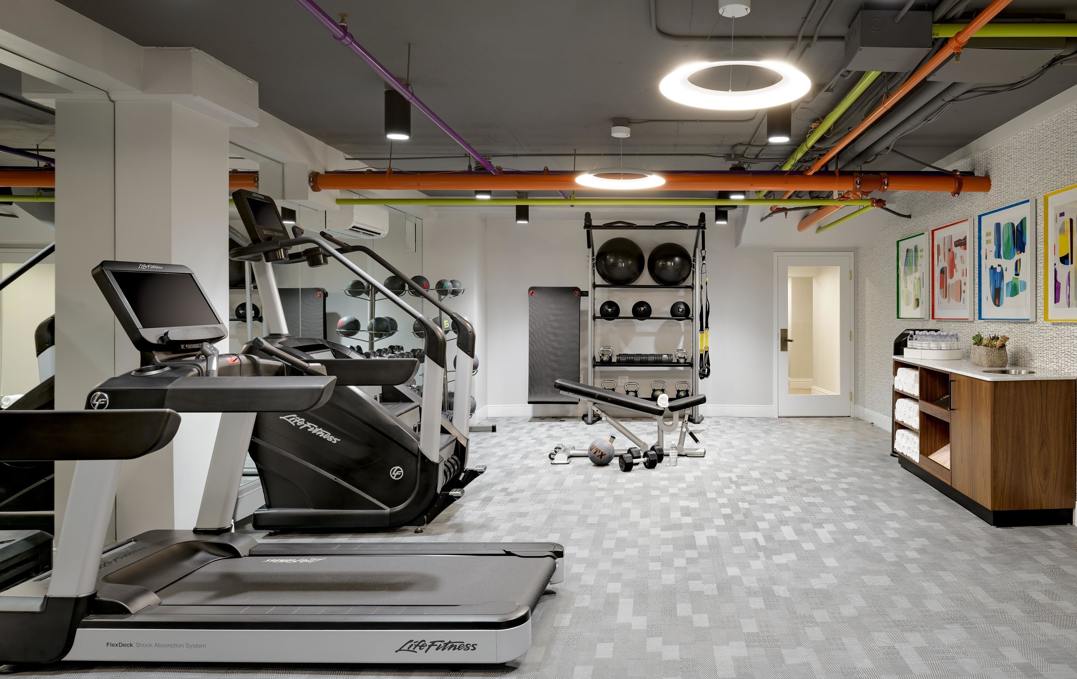 A gym with treadmills, weights, and a mirrored wall.