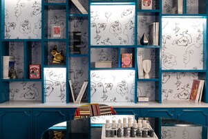 Una habitación con pared azul, una pizarra con dibujos y una estantería con libros y adornos.