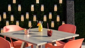 An outdoor dining area with a table, chairs, and a wall of hanging lights.