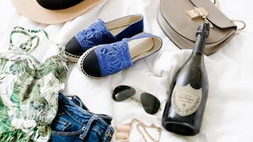 A bottle of champagne, a straw hat, a pair of blue shoes, a handbag, a pair of sunglasses, and a denim jacket.