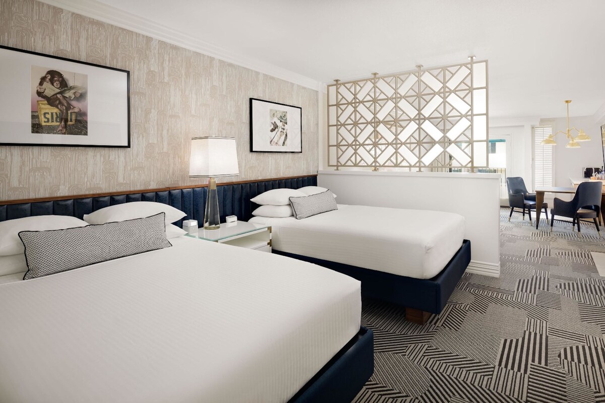Une chambre d’hôtel avec deux lits, un bureau, une chaise, une lampe et un paravent décoratif.