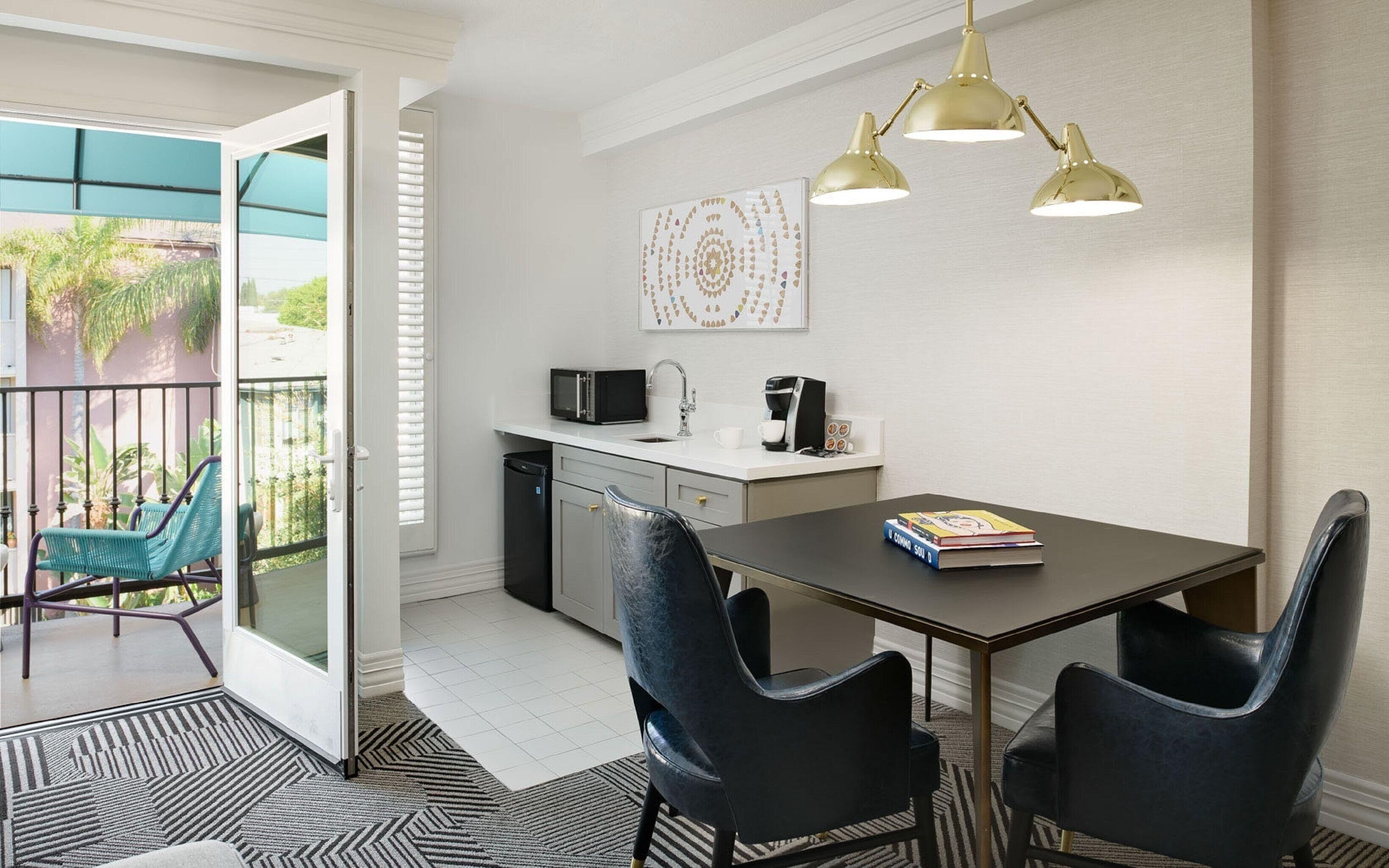 A modern kitchen with a dining area, a balcony with chairs, and a coffee machine.