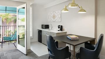 A modern kitchen with a dining area, a balcony with chairs, and a coffee machine.