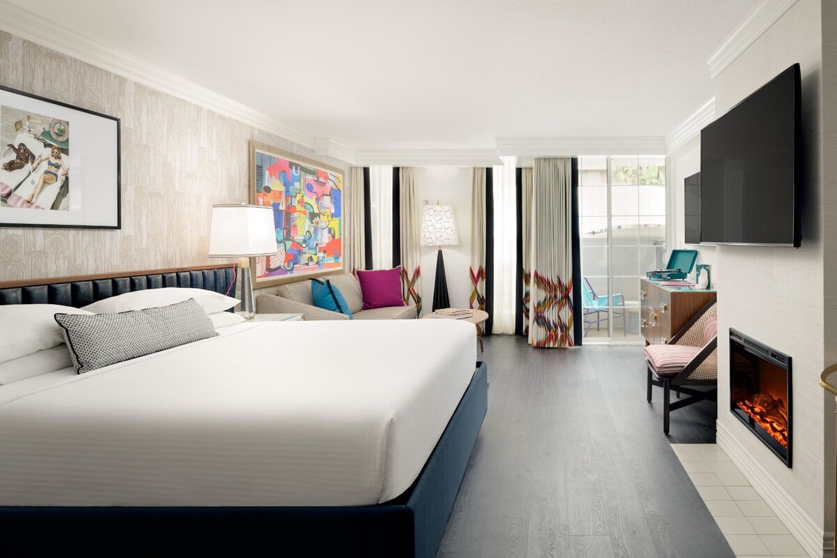 Une chambre d’hôtel avec un grand lit, une télévision, une cheminée et un balcon avec vue.