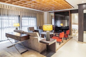 Une chambre d’hôtel moderne équipée d’un canapé, de fauteuils, d’un bureau, d’un coin repas et d’un lit.