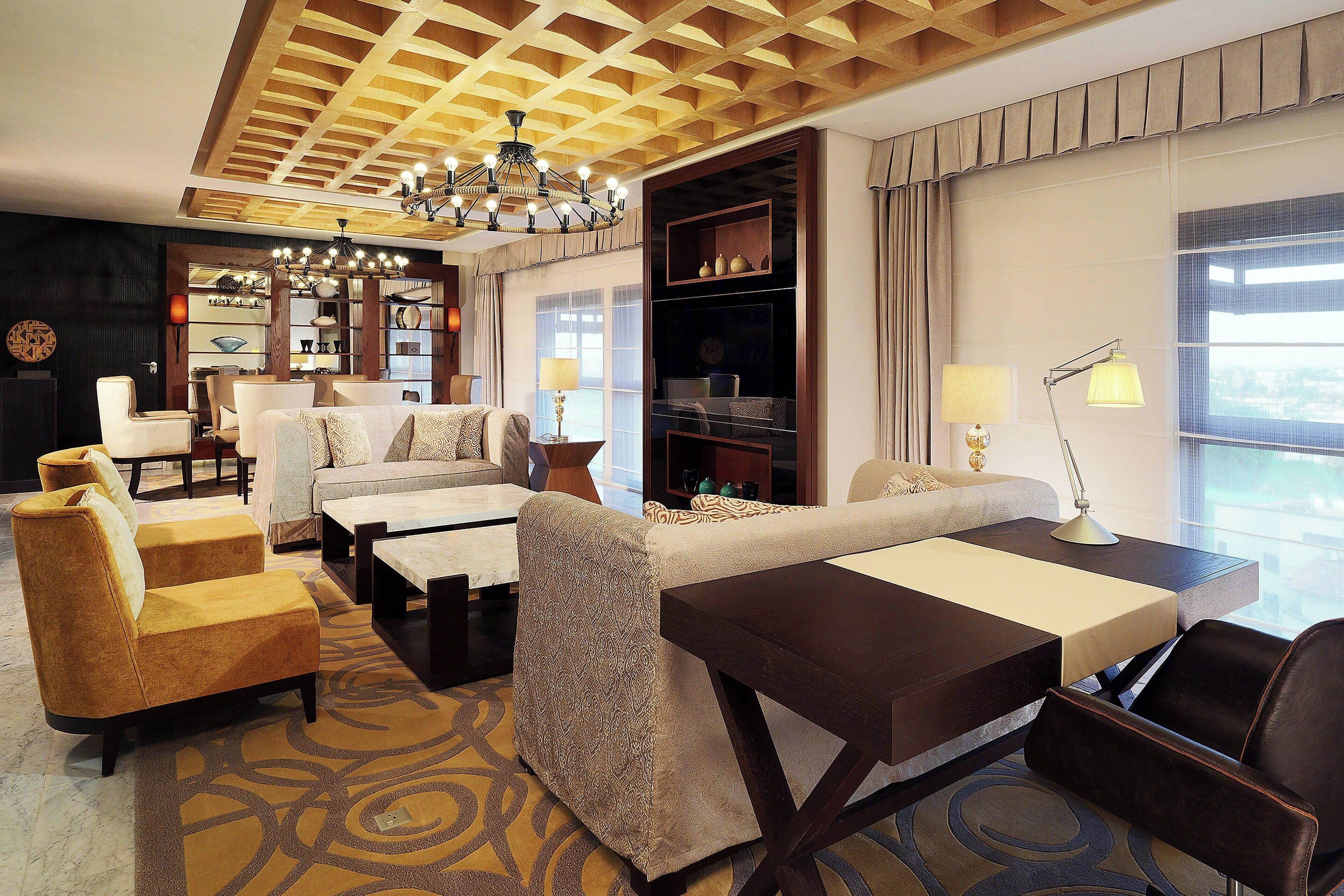 Ein Hotelzimmer mit modernem Design, ausgestattet mit einer Couch, Sesseln, einem Schreibtisch und einem Bücherregal.