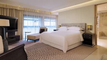 Una habitación de hotel con una cama grande, televisión, zona de estar y baño.
