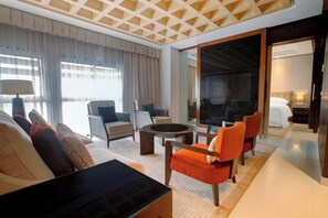 Relax in a spacious room with a large bed, sofa, and armchairs, plus a balcony with a sliding glass door.