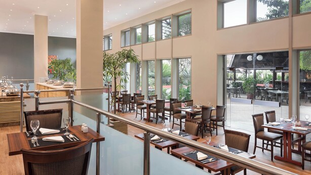 A spacious restaurant with high ceilings, large windows, and a variety of seating arrangements. - Sheraton Lagos Hotel (Lagos)