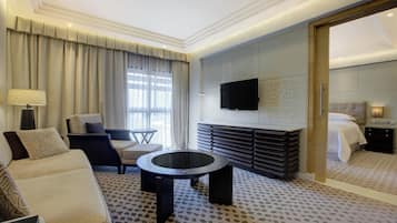 Una habitación de hotel con sofá, sillón, mesa de centro redonda y cama.
