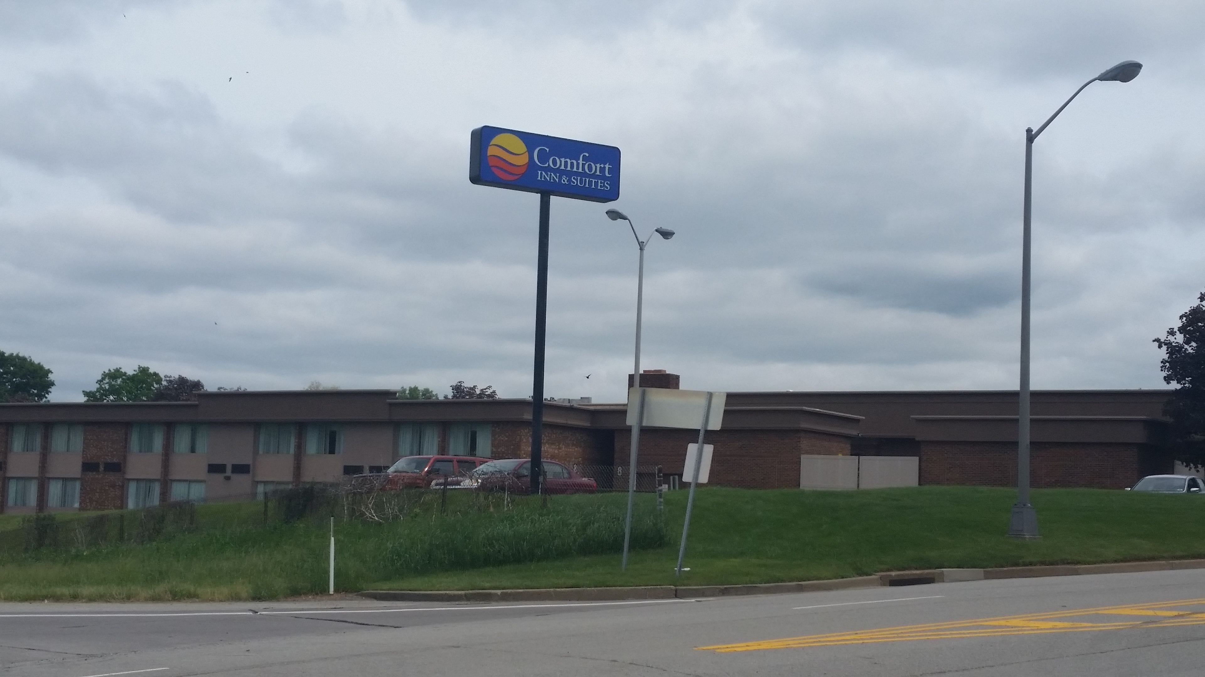 Une enseigne « Comfort Inn & Suites », un bâtiment à la façade en briques et un espace verdoyant avec une rue en contrebas.
