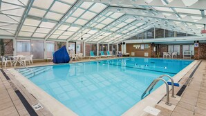 An indoor swimming pool with clear water, surrounded by lounge chairs and a covered roof structure. - Comfort Inn & Suites Pittsburgh Fox Chapel (Pittsburgh)