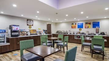 Angolo colazione con posti a sedere, macchina del caffè e banco buffet.