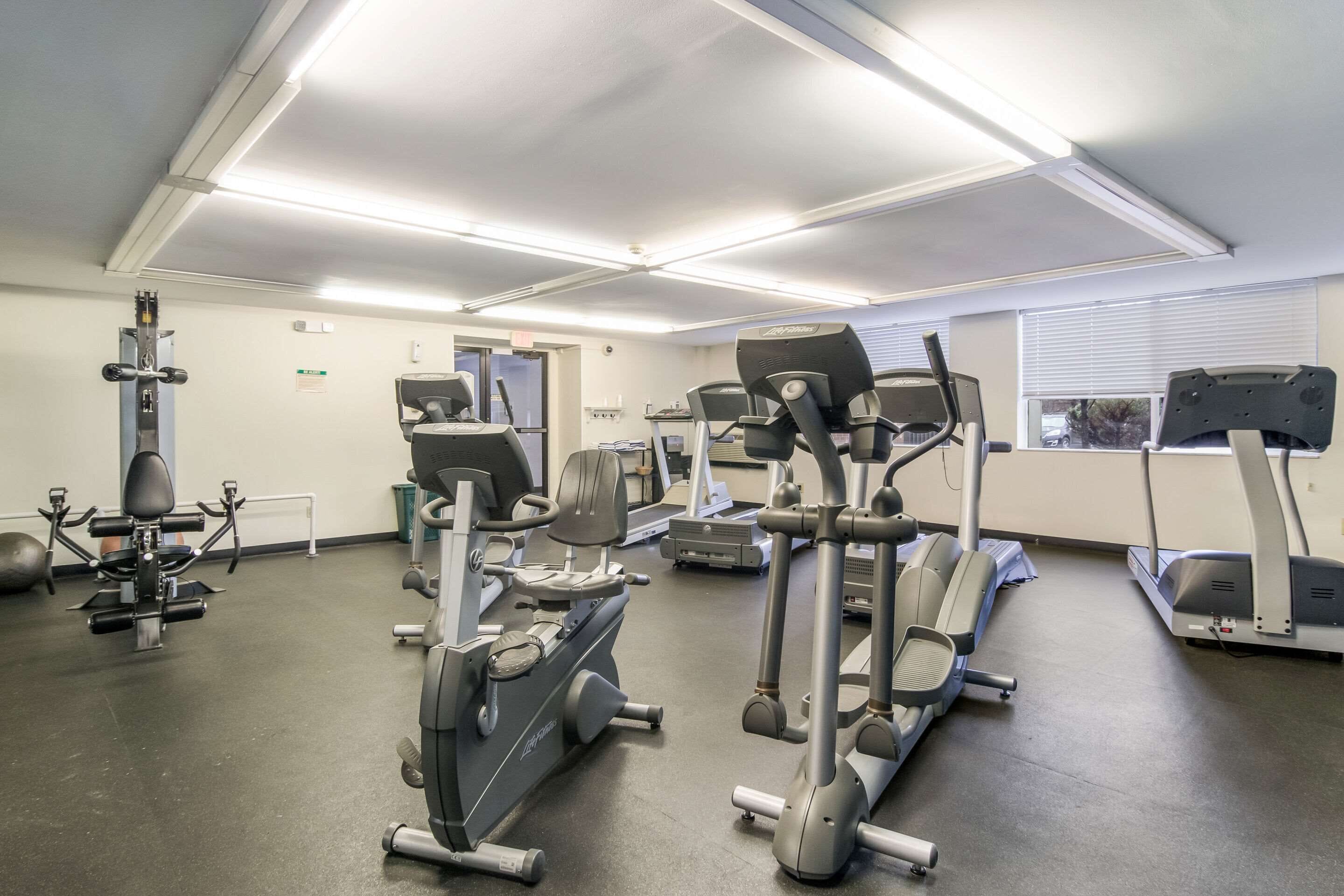 A gym with various exercise equipment including treadmills, elliptical machines, and weight machines.