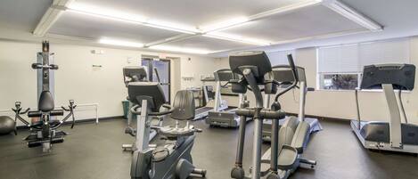 A gym with various exercise equipment including treadmills, elliptical machines, and weight machines.