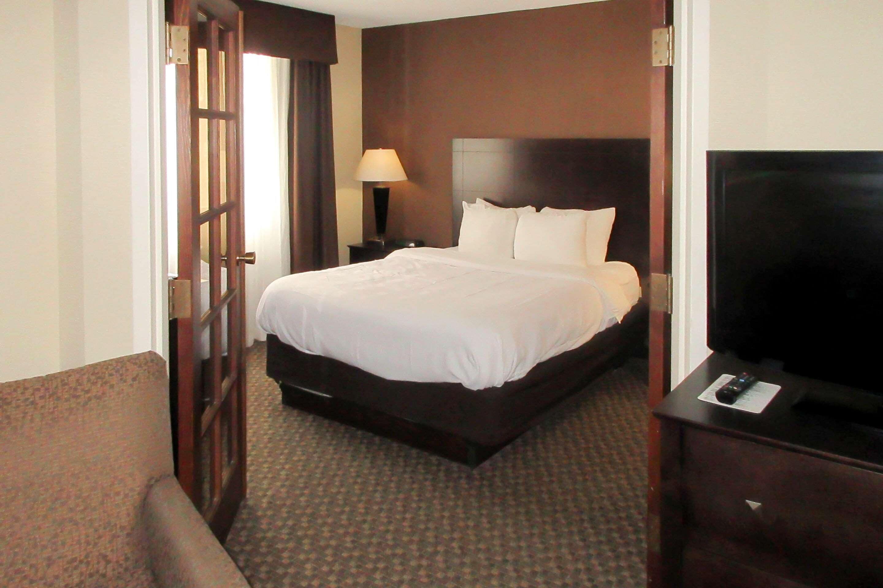 Una habitación de hotel con cama, televisión, lámpara y puerta.