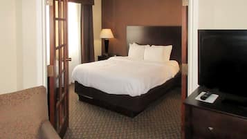 Una habitación de hotel con cama, televisión, lámpara y puerta.