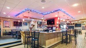 A bar area with wooden bar counters, black bar stools, and a television screen. - Comfort Inn & Suites Pittsburgh Fox Chapel (Pittsburgh)