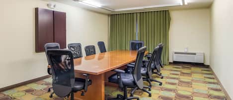 A conference room with a long table, six chairs, a brown cabinet, a green curtain, and an air conditioning unit.