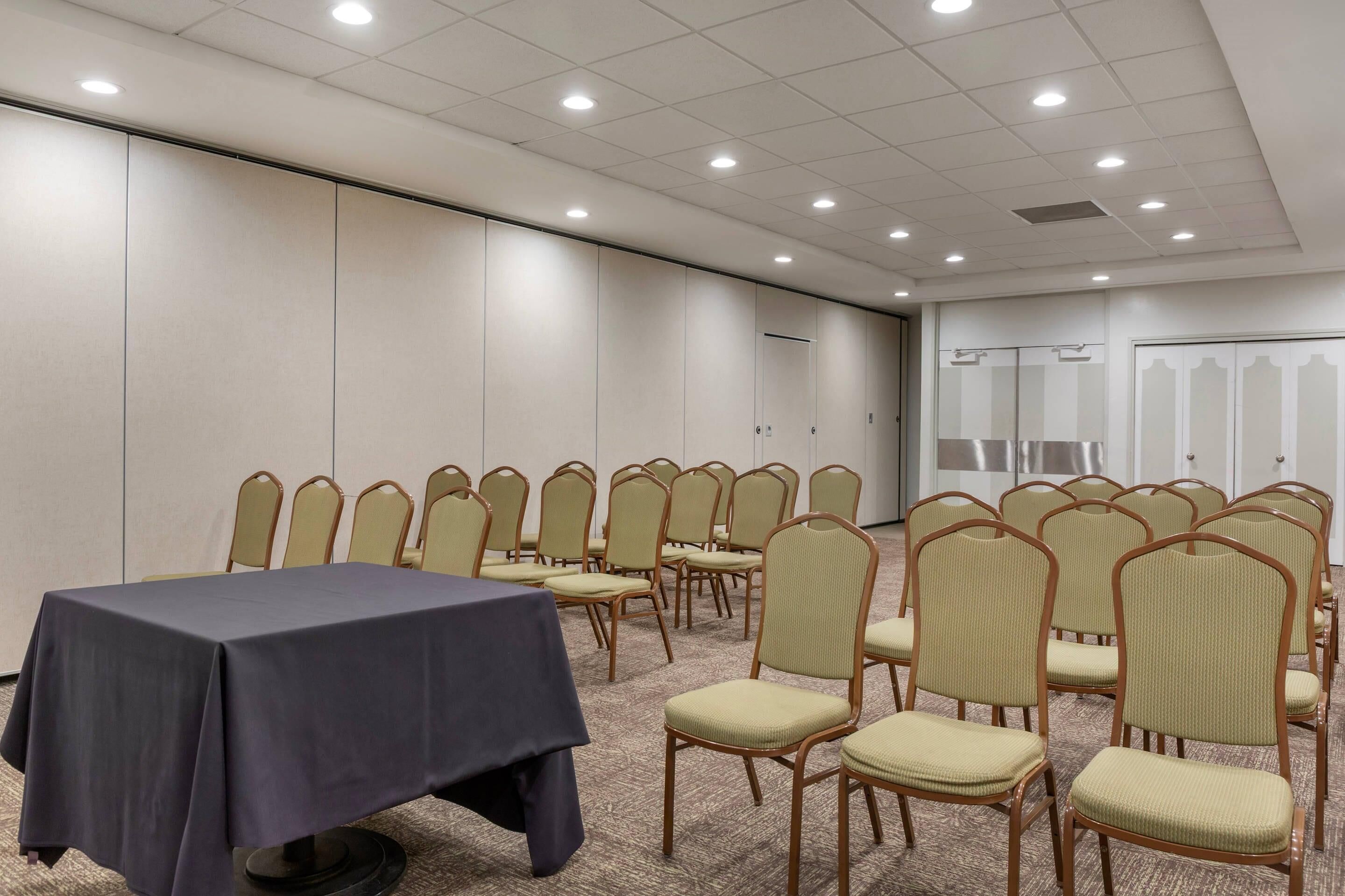 Un salón de conferencias con una mesa y sillas dispuestas para una reunión.