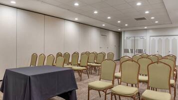 Un salón de conferencias con una mesa y sillas dispuestas para una reunión.