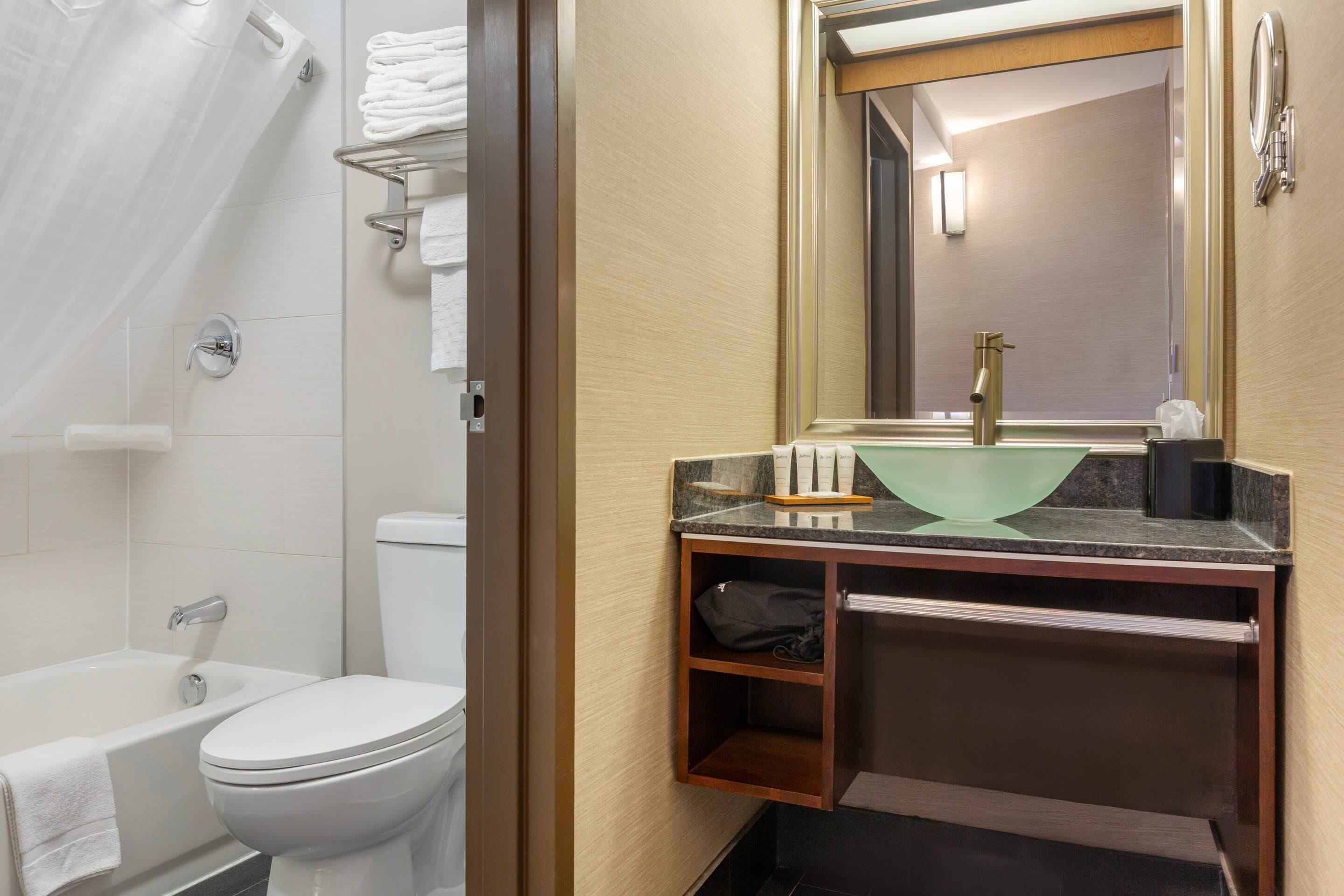 A bathroom with a bathtub, toilet, sink, and mirror.