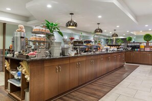 Een moderne keuken met een centraal eiland, roestvrijstalen apparatuur en verschillende etenswaren op planken uitgestald.