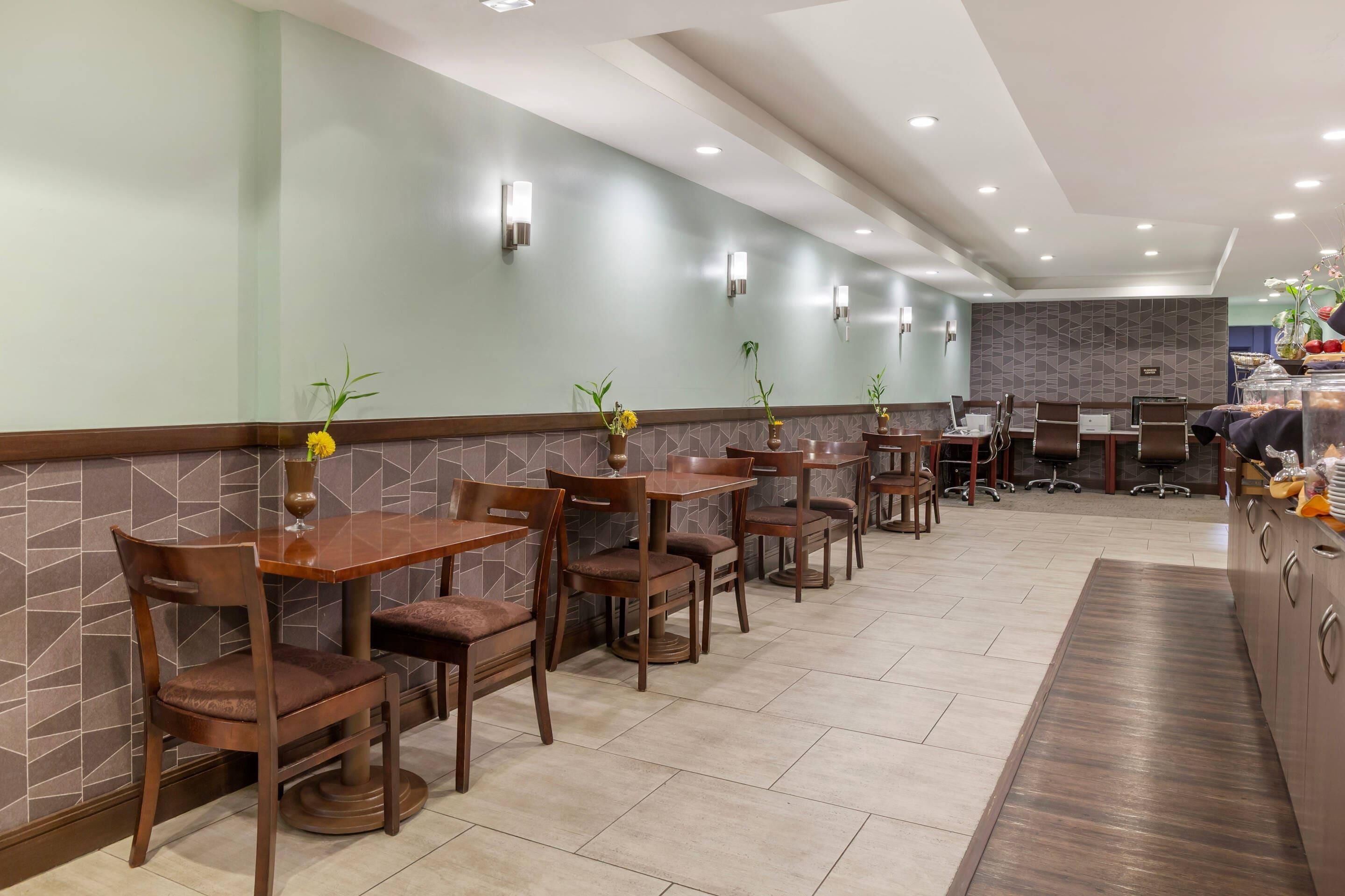 A restaurant with multiple tables and chairs, a counter with a display of food items, and a tiled floor.