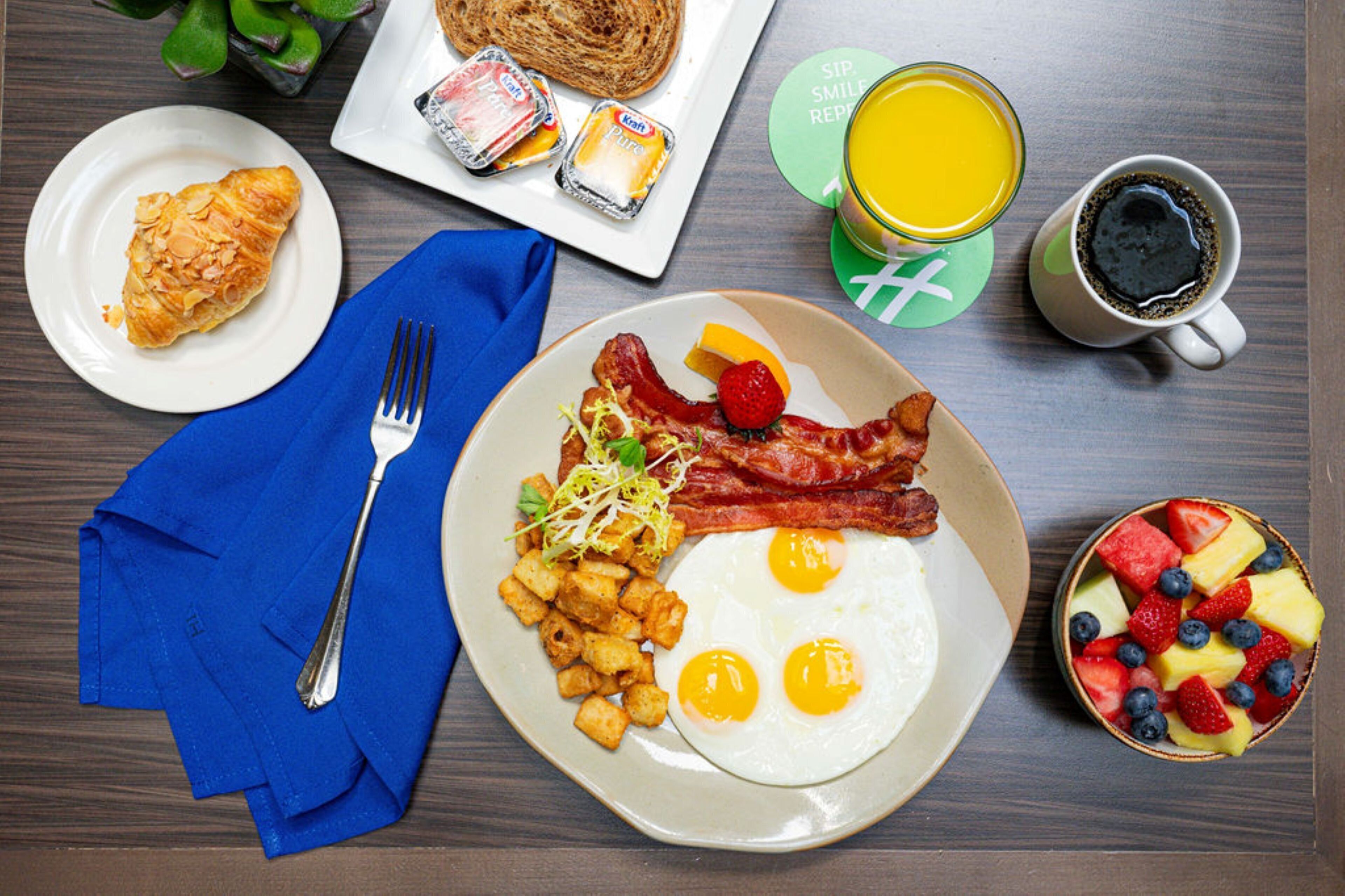 A breakfast plate with eggs, bacon, hash browns, and toast, accompanied by a cup of coffee and a glass of orange juice.