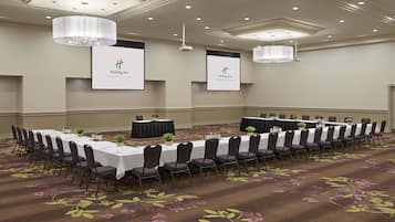 A conference room with a long table, chairs, and floral carpet.
